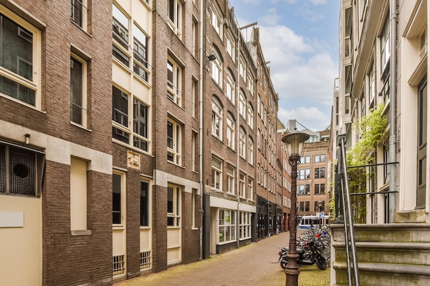 Een smalle straat in het oude gedeelte van amsterdam met aan beide kanten geparkeerde fietsen en gebouwen aan de rechterkant