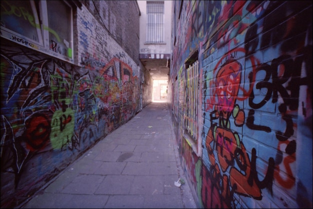 Een smalle straat tussen graffiti muren.
