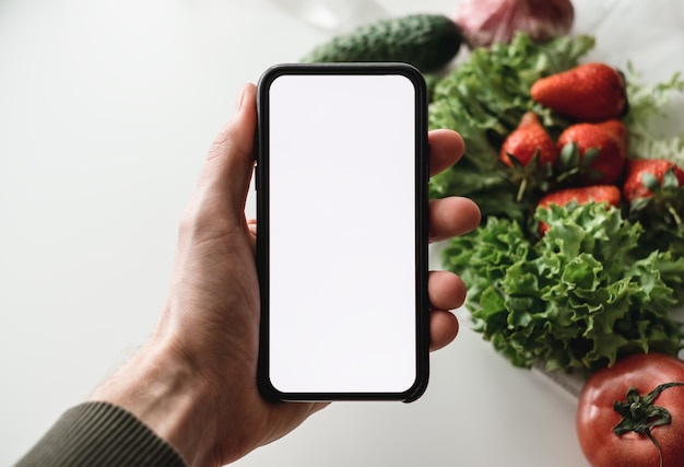 Een smartphone met een leeg scherm en verse groenten