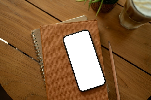 Een smartphonemodel met wit scherm op een boek op een houten tafelstudietafel