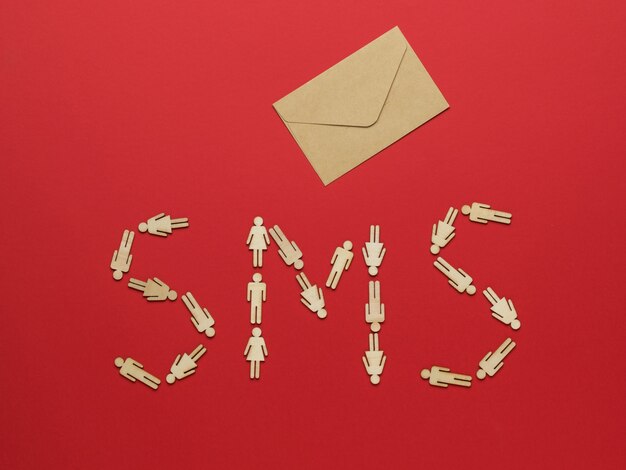 Een SMS-inscriptie gemaakt van beeldjes van kleine mannen en een postenvelop op een rode achtergrond. Het concept van communicatie tussen mensen.