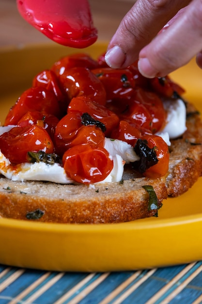 Foto een snack bereiden met een plakje brood van natuurlijke fermentatie gevuld met tomaten confit buffalo mozzarella en een druppel balsamische azijn reductie met suikerriet melasse