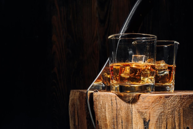 Een snede van een boom gesneden met een bijl er zijn twee glazen whisky en ijs erop rust concept na een zware dag op het werk whisky en hout