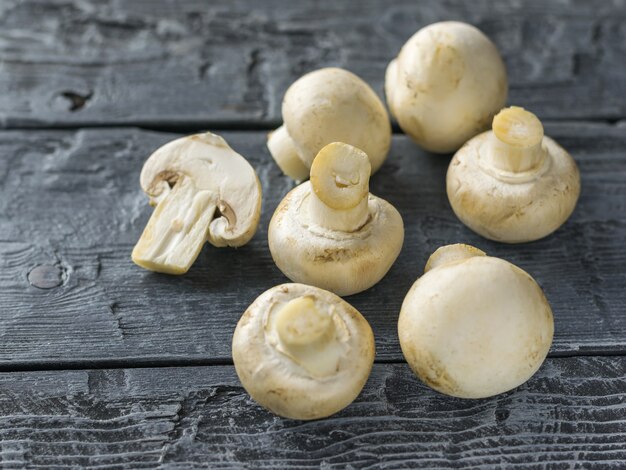 Een snee en zes hele paddestoelen op een donkere houten tafel