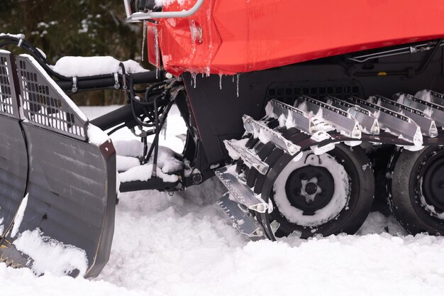 Een sneeuwploeg op rode sporen die in de winter in het bos bij de schuur staan