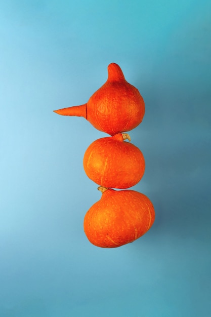 Een sneeuwpop met een wortelneus van drie oranje pompoenen op een blauw