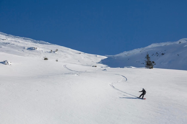 Een snowboarder maakt een steile bocht en laat een streep achter in de sneeuw