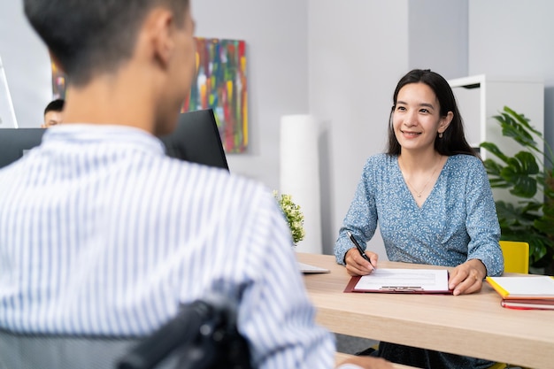 Een sollicitatiegesprek met man met een handicap rolstoelgebruiker mooie vrouw stelt vragen aan jongen