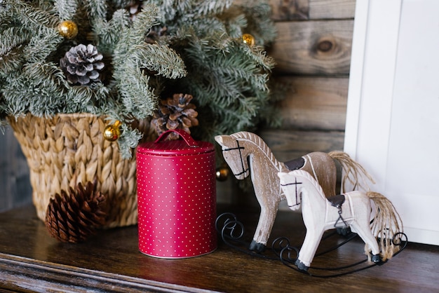 Een souvenirpaard, een frambozenblikje tegen een achtergrond van dennentakken in een rieten mand. Kerst decor