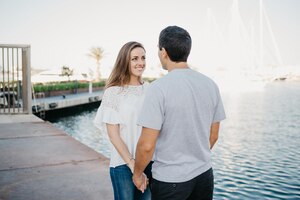 Een spaanse stijlvolle man houdt de handen vast van zijn lachende brunette vriendin in spanje
