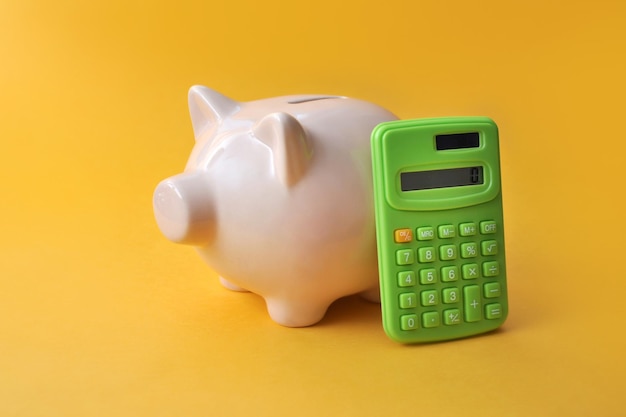 Een spaarvarken en een rekenmachine ernaast een symbool voor het berekenen van financiën