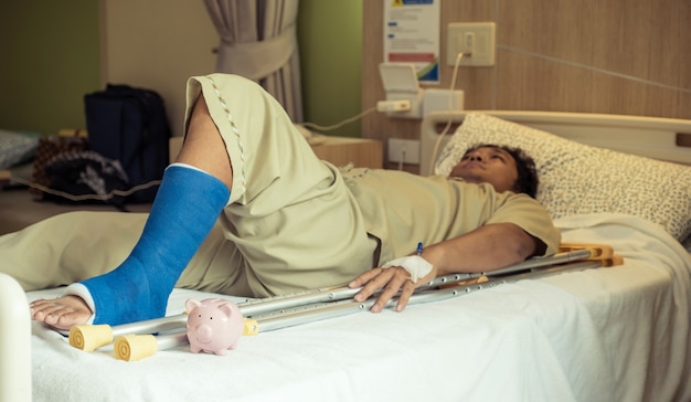 Foto een spaarvarken met het been van een man gebruikt krukken om te lopen na een operatie herstel letsel gebroken botten.