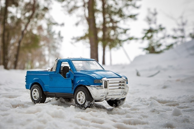 Een speelgoed blauwe pick-up truck in het winterbos op de weg staande met open deur