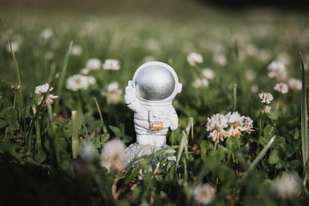 een speelgoedastronaut staat in het hoge gras en zwaait met zijn hand