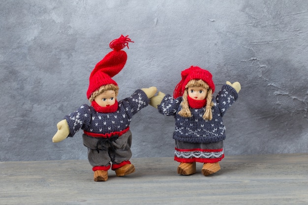 een speelgoedjongen en -meisje in winterkleren houden elkaars hand vast