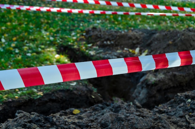 Een spervuur van gestreepte tape rond de put van een uitgegraven gazon zorgt voor veiligheid op de plaats van reparatiewerkzaamheden