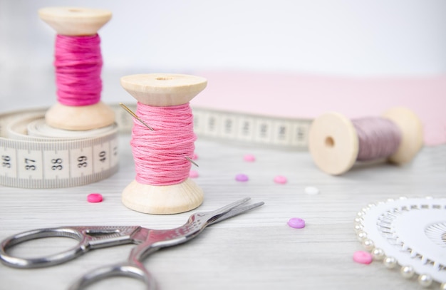 Een spoel van draadschaareen naald en knopen op een houten tafel