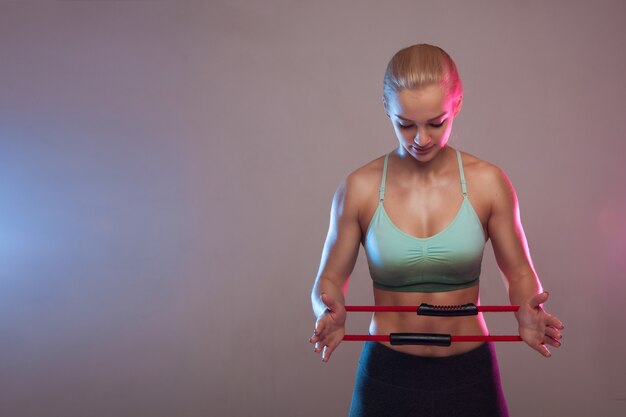 Een sportief meisje heeft een expander voor fitness, de spieren zijn gespannen. Fitness, sport, training, mensen en levensstijl