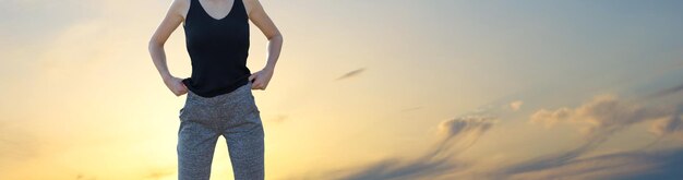 Een sportief slank meisje in legging en een top staat met een trainingsmat, rustend tussen de oefeningen.