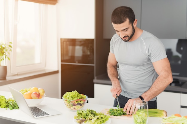 Een sportieve man bereidt een salade in de keuken.