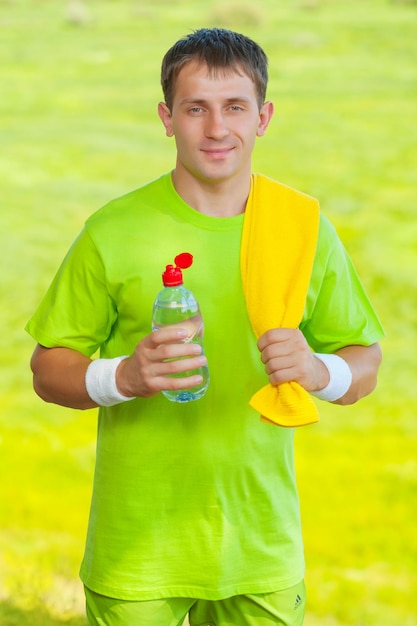 Een sportman die een fles water vasthoudt en naar de camera kijkt