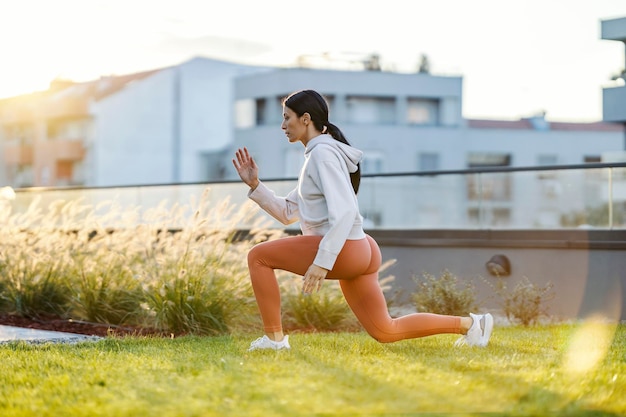Een sportvrouw doet een walking lunge in het stadspark