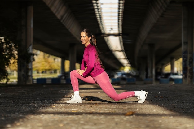 Een sportvrouw strekt haar been uit en bereidt zich voor op joggen in de open lucht