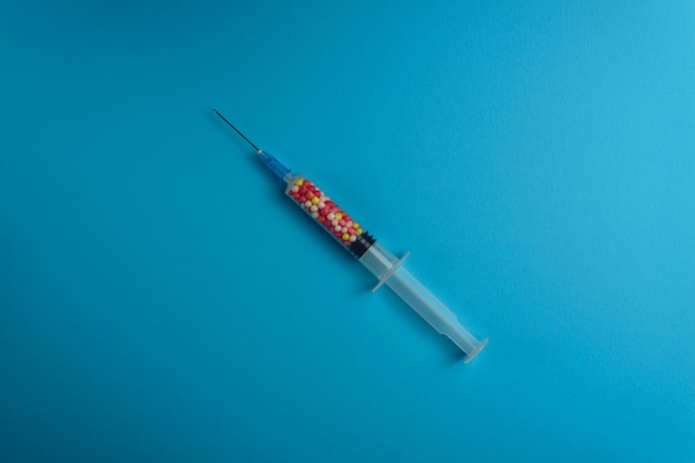 Foto een spuit gevuld met kleurrijke nanoballen op een blauwe achtergrond innovatief medisch concept