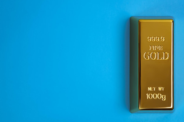 Een staaf van goudmetaal van puur briljant diagonaal op een blauwe achtergrond