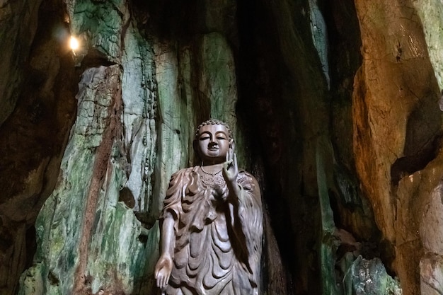Een standbeeld van Boeddha staat in een grot met een licht op het plafond.