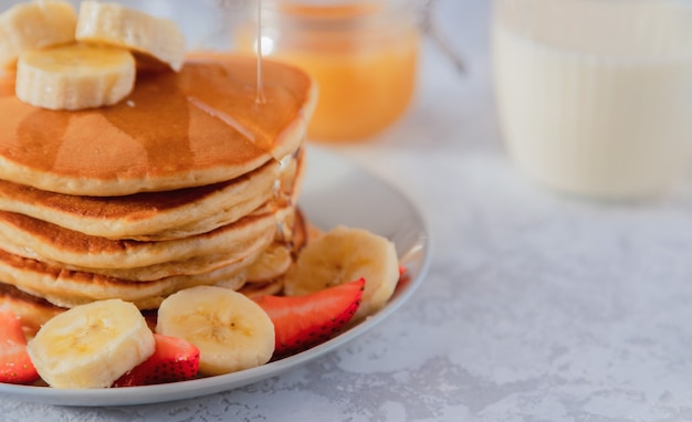 Een stapel amerikaanse pannenkoeken wordt bestrooid met agavesiroop of honing