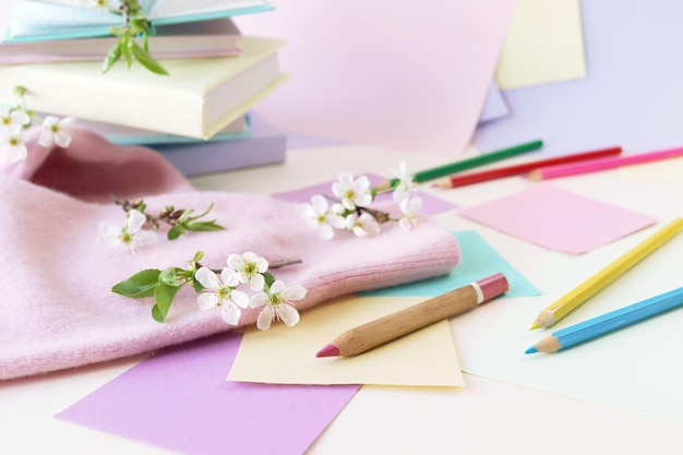 Een stapel boeken leerboeken potloden blocnotes en takjes kersenbloesem op een tafel