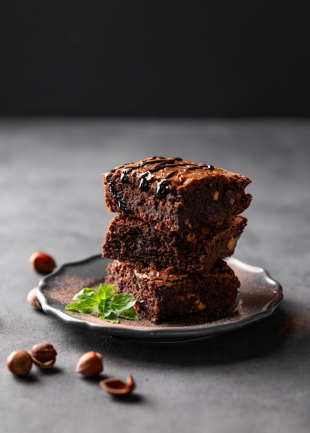 Een stapel chocolade brownies met munt hazelnoten en gezouten karamel op een donkere achtergrond met noten