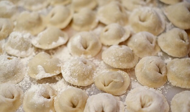 Een stapel dumplings met meel op de tafel.