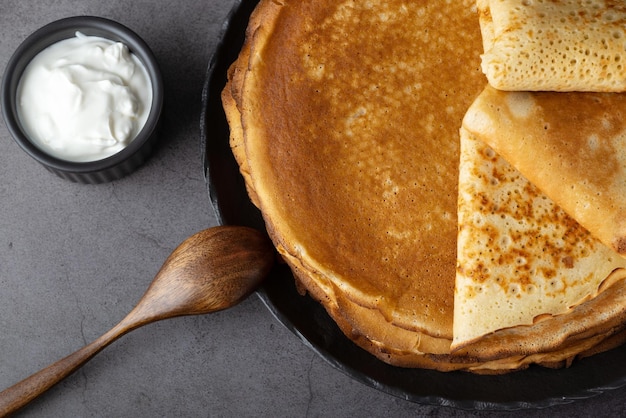 Een stapel dunne pannenkoeken met verse zure room