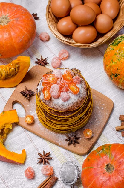 Een stapel eigengemaakte pompoenpunkcakes met poedersuiker en geglaceerde kumquat