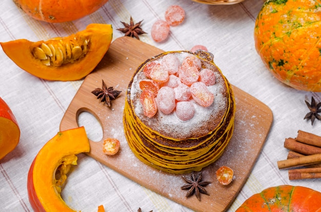 Een stapel eigengemaakte pompoenpunkcakes met poedersuiker en geglaceerde kumquat