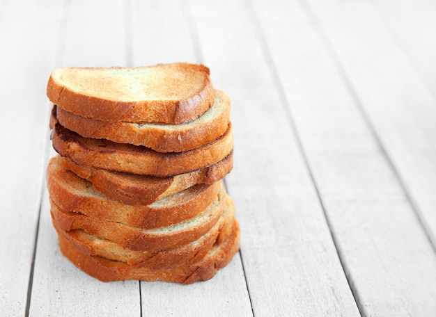 Een stapel geroosterde sneetjes brood voor het ontbijt, op een witte houten achtergrond