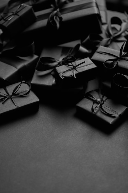 Foto een stapel geschenken in zwarte dozen van verschillende grootte, geplaatst op stapel. kerstconcept. donkere sfeer en stijl. bovenaanzicht plat gelegd