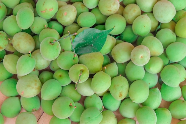 Een stapel groene pruimen op een houten tafel.