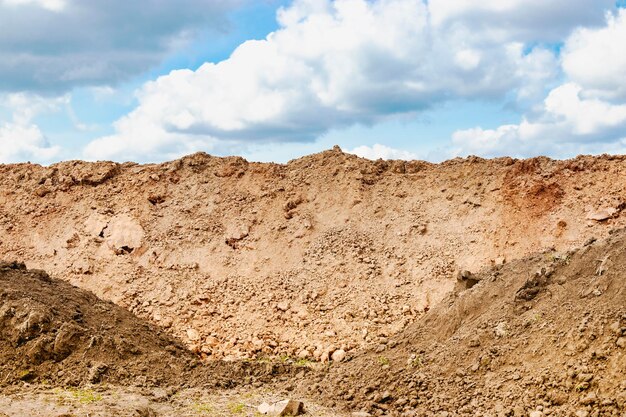 Een stapel grond gegraven uit een greppel tegen een blauwe bewolkte hemel grondwerken op de bouwplaats