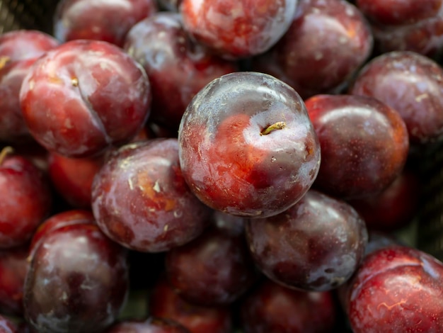 Een stapel rode pruimenvruchten Prunus americana in de supermarkt