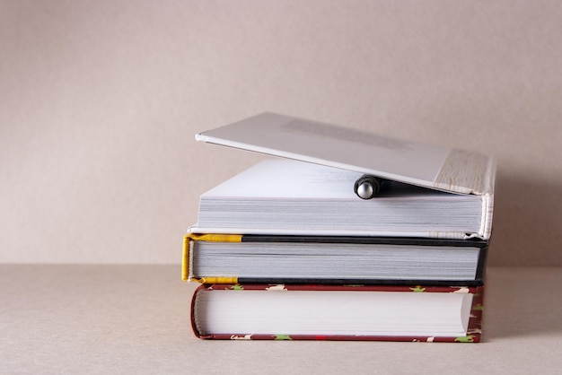 Een stapel schoolboeken en een balpen op een beige achtergrond