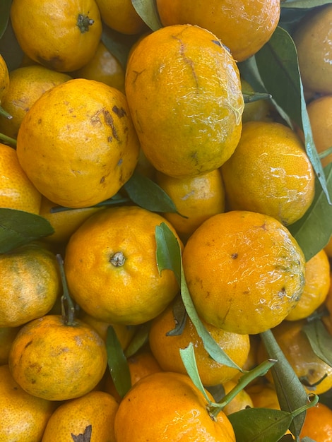 Een stapel sinaasappels met groene bladeren erop