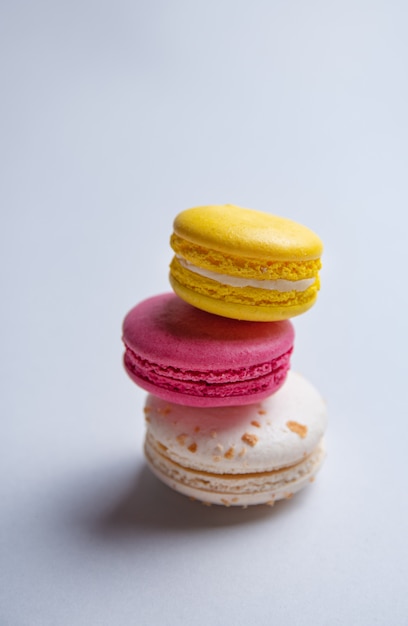 Een stapel van drie heerlijke macaron en roze, wit en geel op een grijze achtergrond