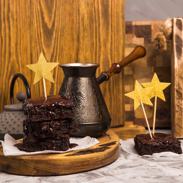 Een stapel vierkante brownie stukken gegoten met chocolade op een houten bord. Heerlijk dessert