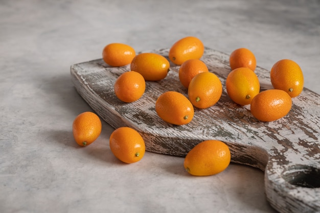 Een stapel vitamine kumquat-vruchten op het oude houten bord op grijs