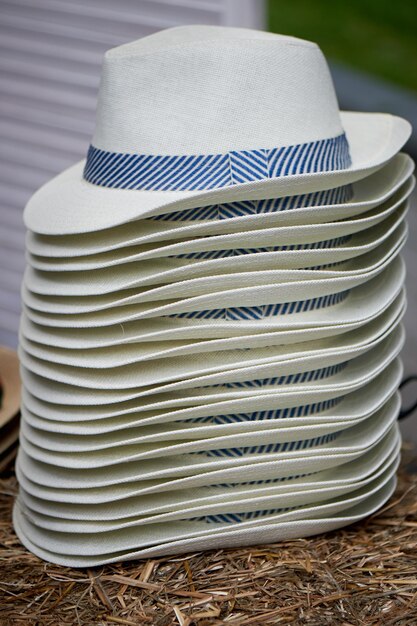 Een stapel witte hoeden met een blauw lint verkoop van hoeden in italiaanse stijl