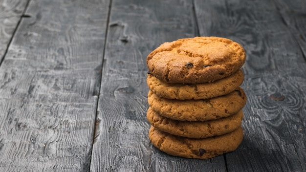 Een stapel zelfgemaakte koekjes met chocoladeschilfers op een zwarte houten tafel