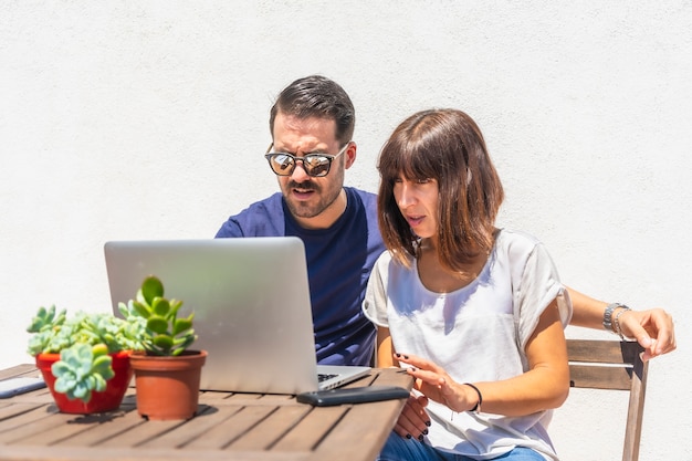 Een stel dat een videogesprek voert met vrienden op de computer op het terras